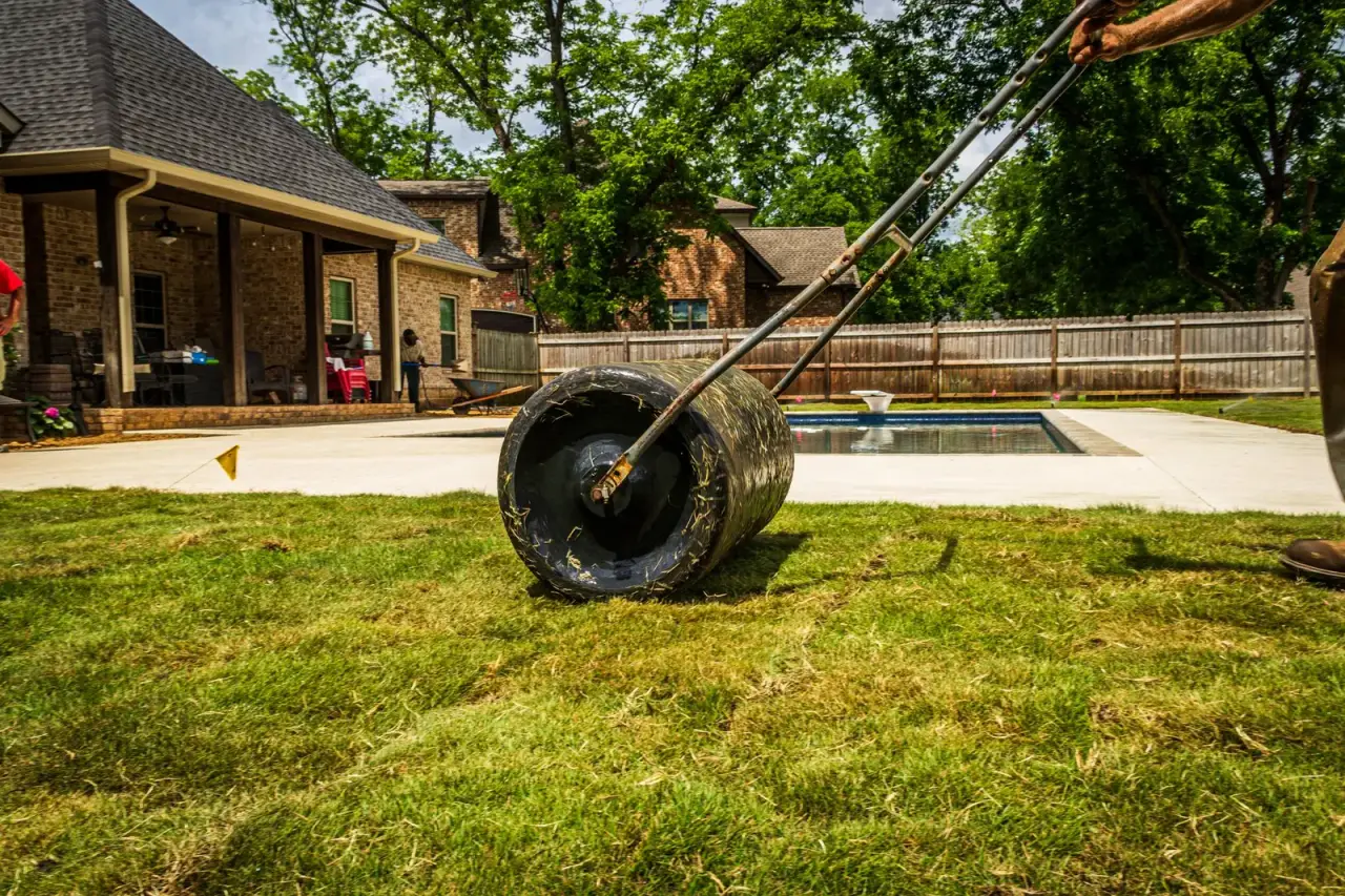 Paysagiste posant du gazon en rouleau dans un jardin près d'une piscine