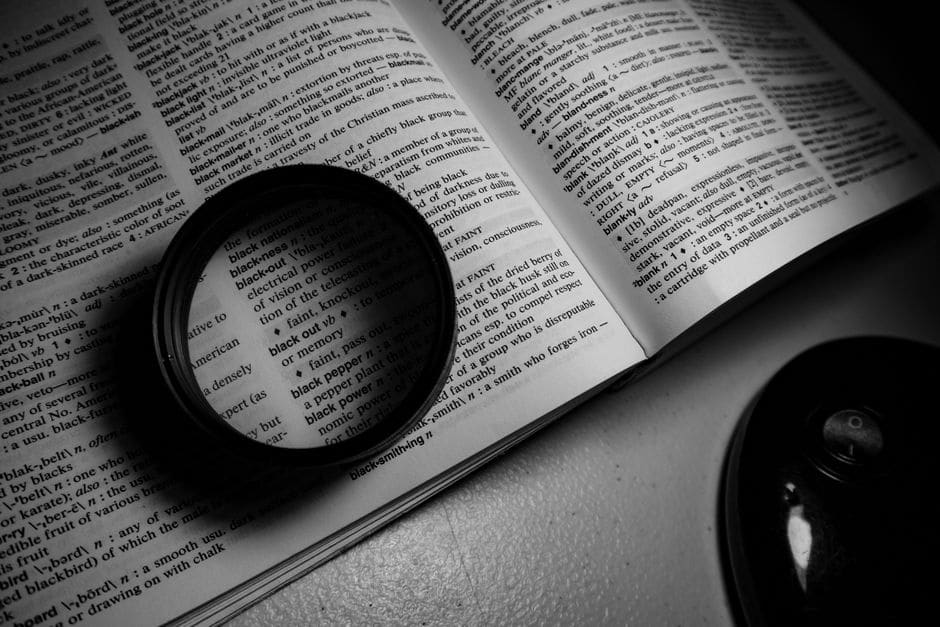 Une loupe posée sur la page d'un dictionnaire ouvert grossit les définitions
