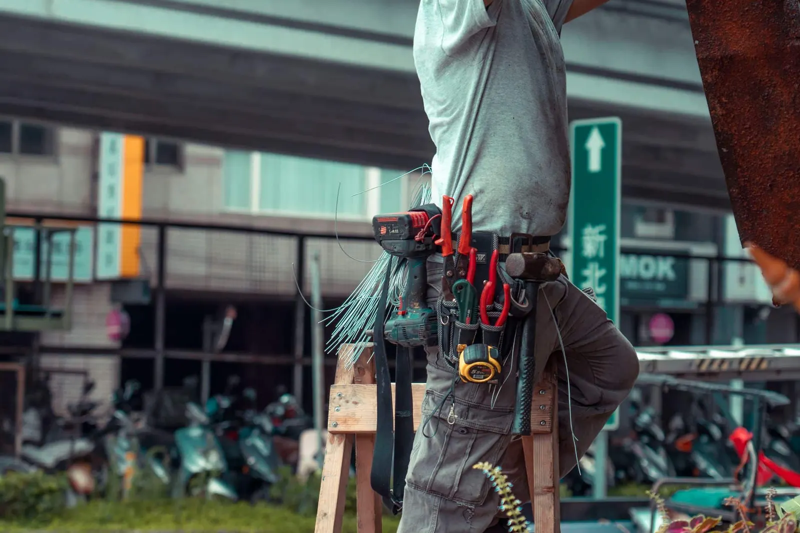 Artisan sur une échelle avec sa ceinture d'outils, en intervention chez un client